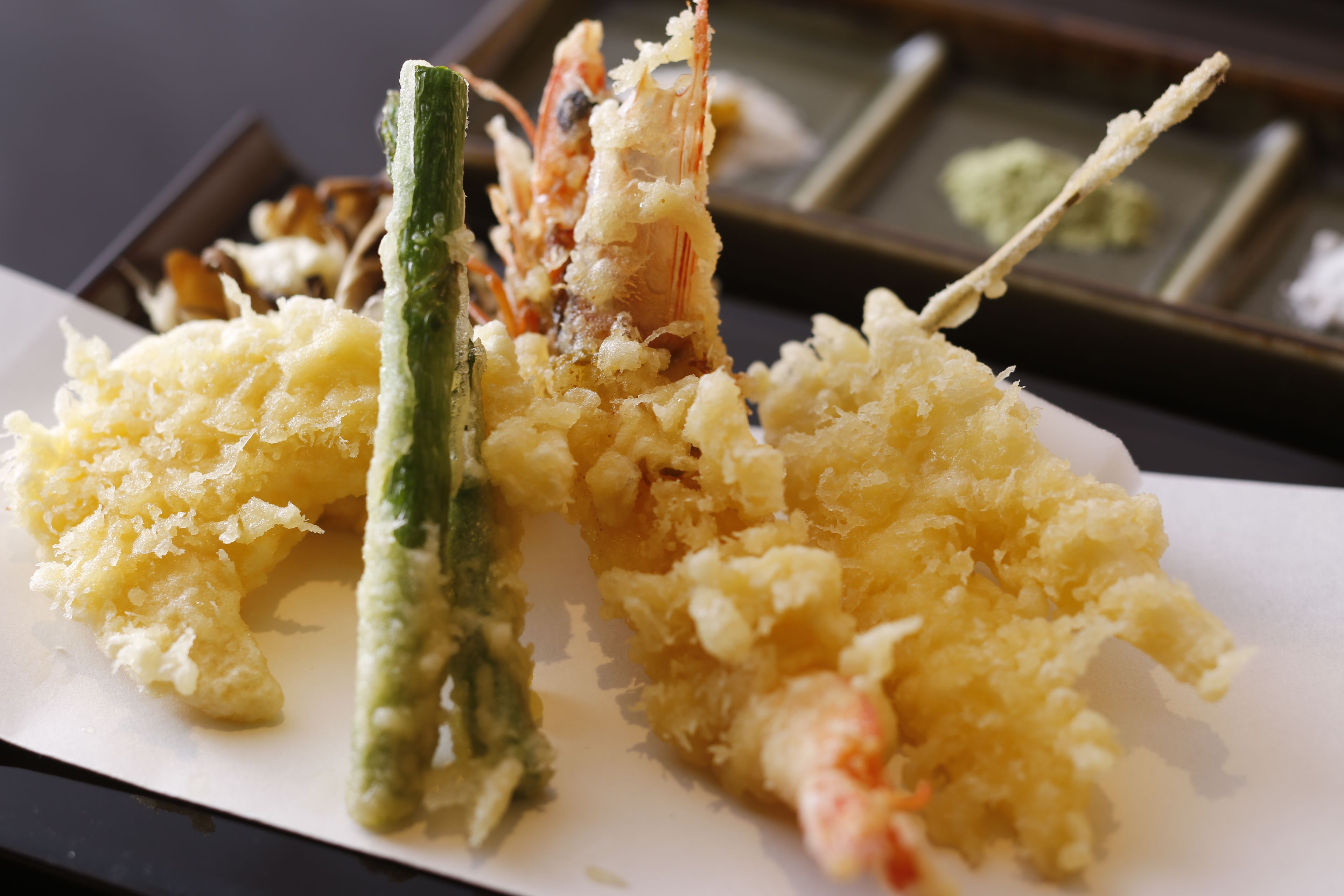 Un plato de tempura con camarones y verduras verdes.