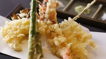 Un plato de tempura con camarones y verduras verdes.