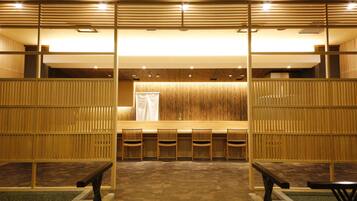 Un interior japonés tradicional con suelo de tatami, separadores de madera y un mostrador de recepción con sillas.