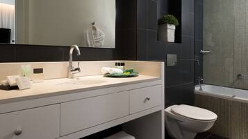 A modern bathroom with a white sink, a mirror, a toilet, and a shower area.