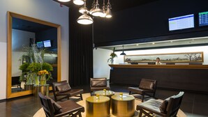 A modern reception area with leather chairs, a reception desk, and a large mirror.