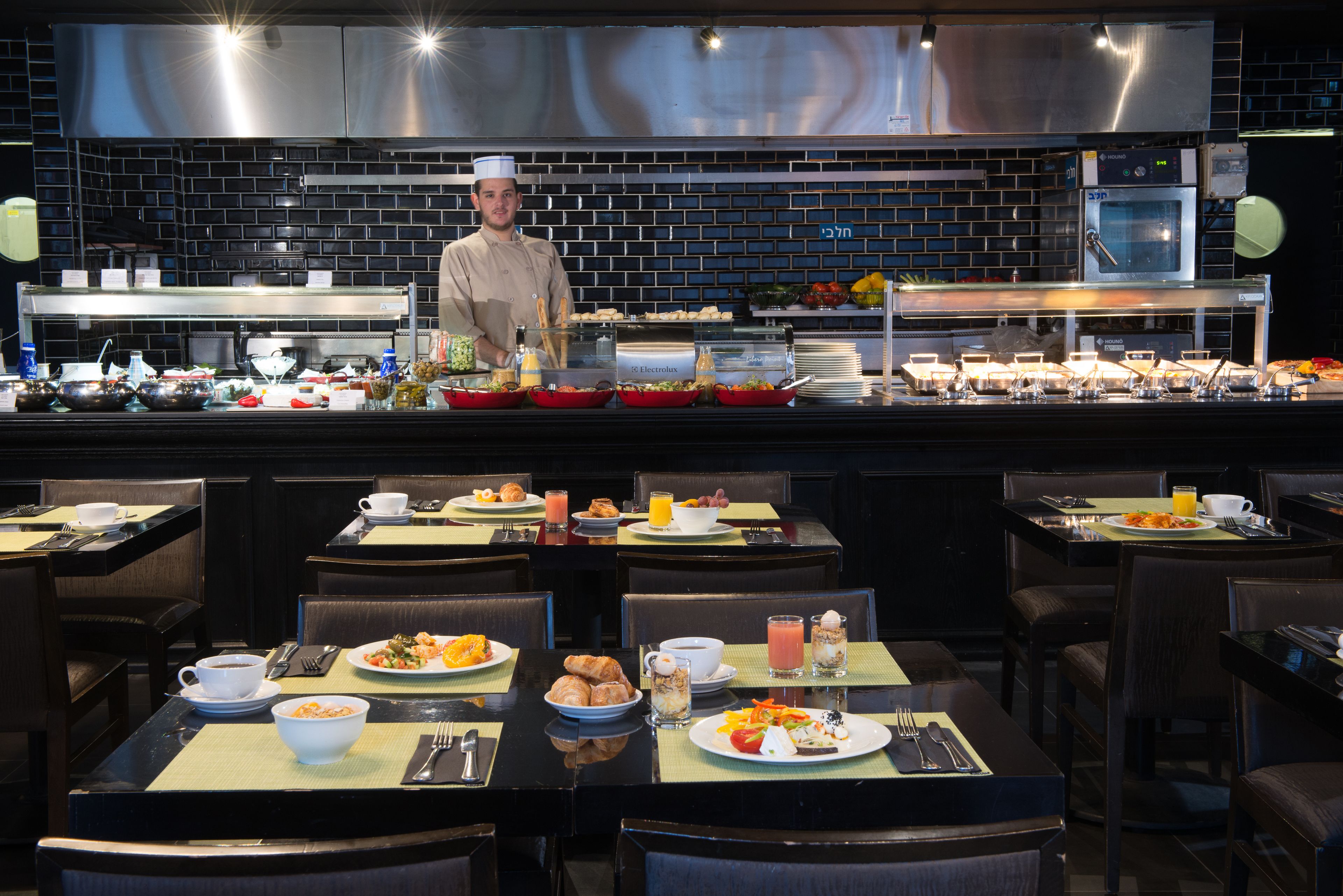 A breakfast buffet with various food items and a chef standing behind the counter.