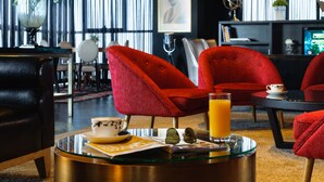 A modern living room with red chairs, a glass coffee table, and a magazine.