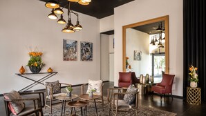 A modern living room with a large mirror, multiple seating areas, and decorative plants.