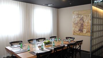 A conference room with a long table, chairs, water bottles, and a decorative plant.