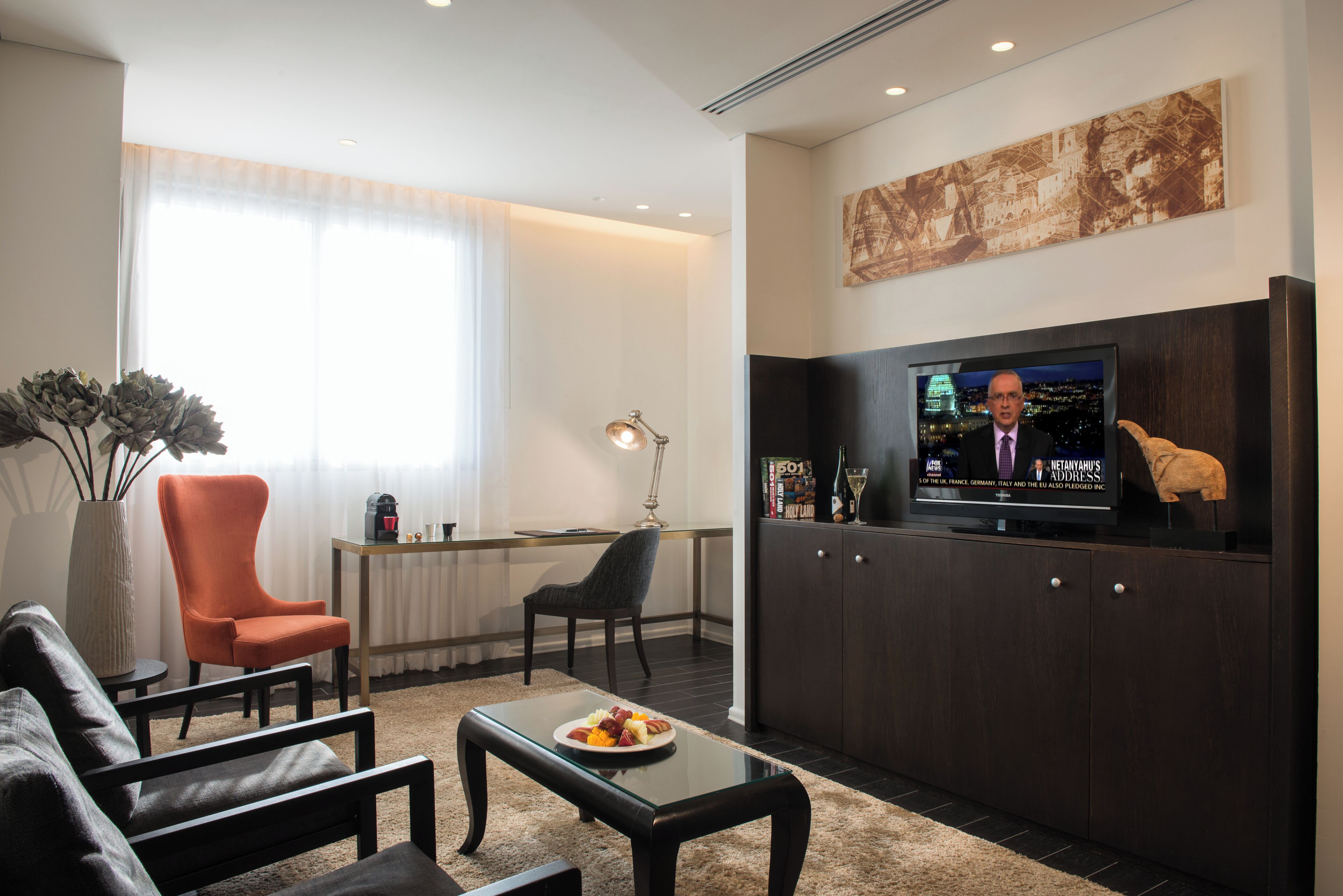 Uma sala de estar moderna com sofá, poltronas, mesa de centro, televisão e uma área de jantar com mesa e cadeiras.