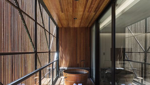 Un intérieur moderne avec un plafond en bois, une grande baignoire en bois et une cloison en verre.