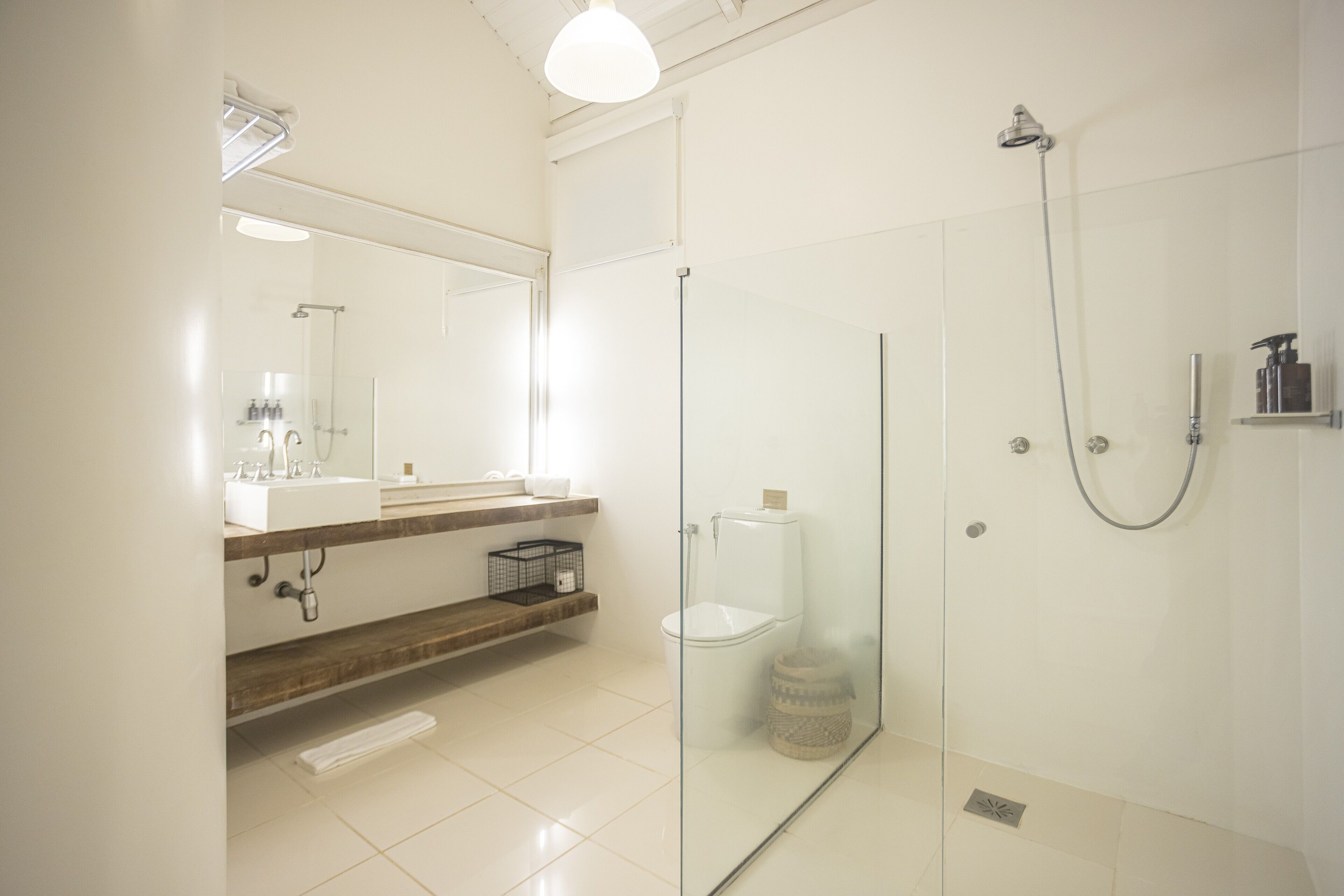 Un baño moderno con ducha envuelta en vidrio, un lavabo blanco y un espejo sobre el mueble.