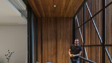 Un interior moderno con suelo de madera, un separador de vidrio y una zona de estar con una mesa y sillas.