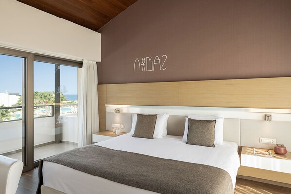 Una habitación de hotel moderna con una cama grande, una mesita de noche y vistas al mar.