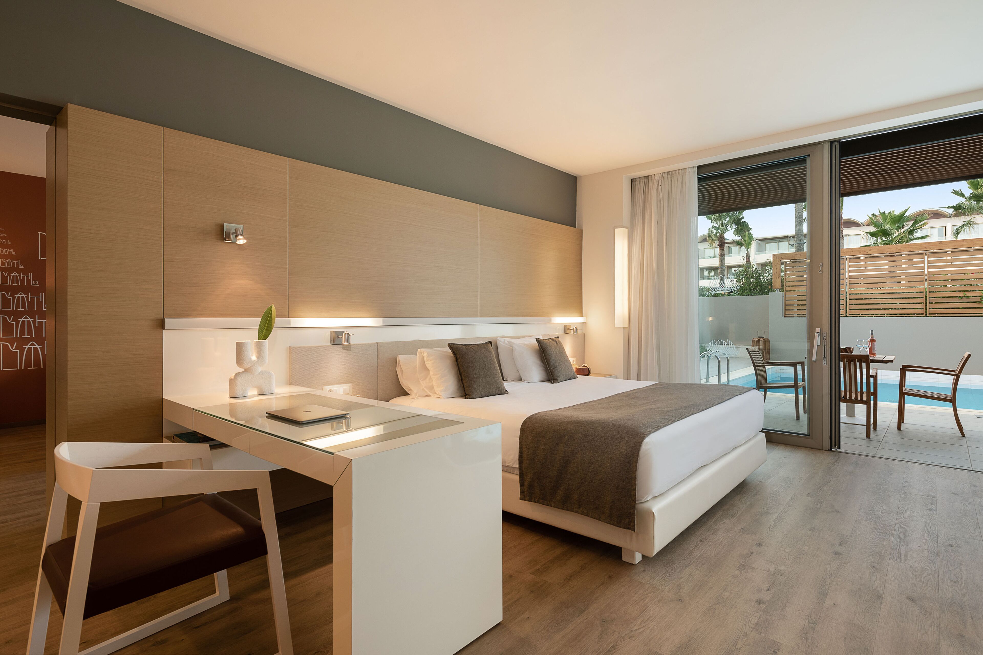 Habitación de hotel moderna con cama, escritorio y vista a la piscina.