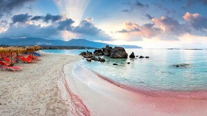 Una playa con aguas cristalinas, arena dorada y rocas.