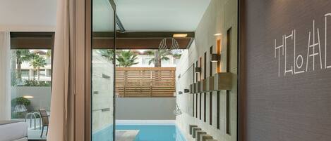 Ein modernes Badezimmer mit einer großen Badewanne, einer in Glas eingefassten Duschkabine und Blick auf einen Pool sowie eine Sitzgelegenheit im Freien.