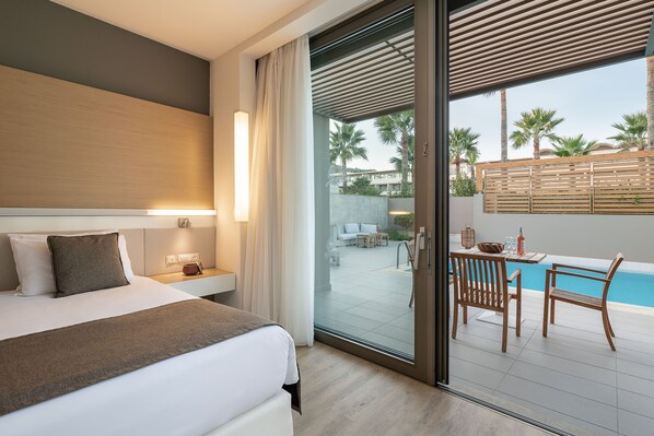 Habitación de hotel con cama, mesita de noche y vista al área de una piscina al aire libre.