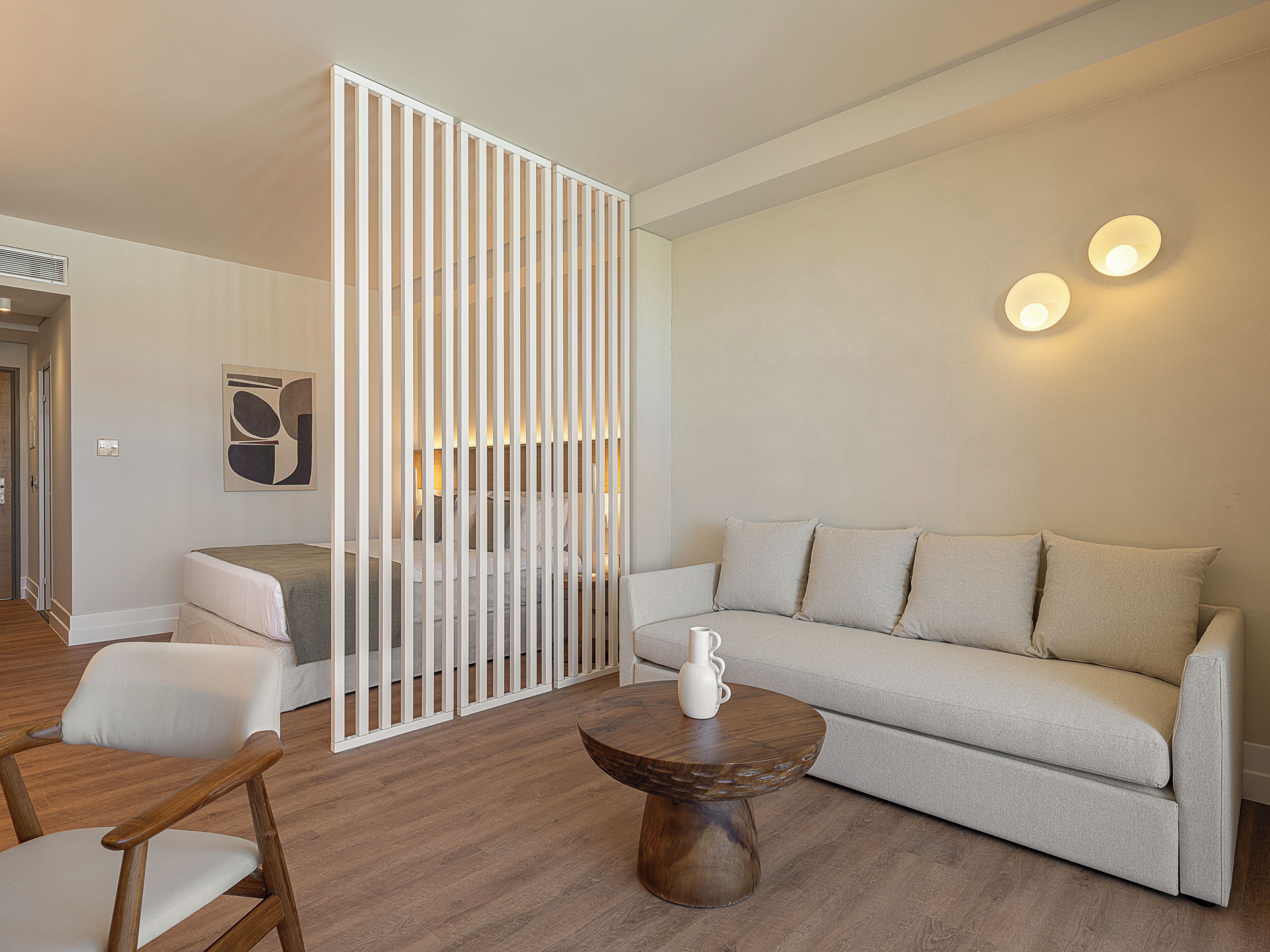 A modern living room with a sofa, a wooden coffee table, and a white partition.