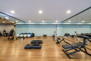Un gimnasio con equipo de ejercicio, espejos y suelo de madera.