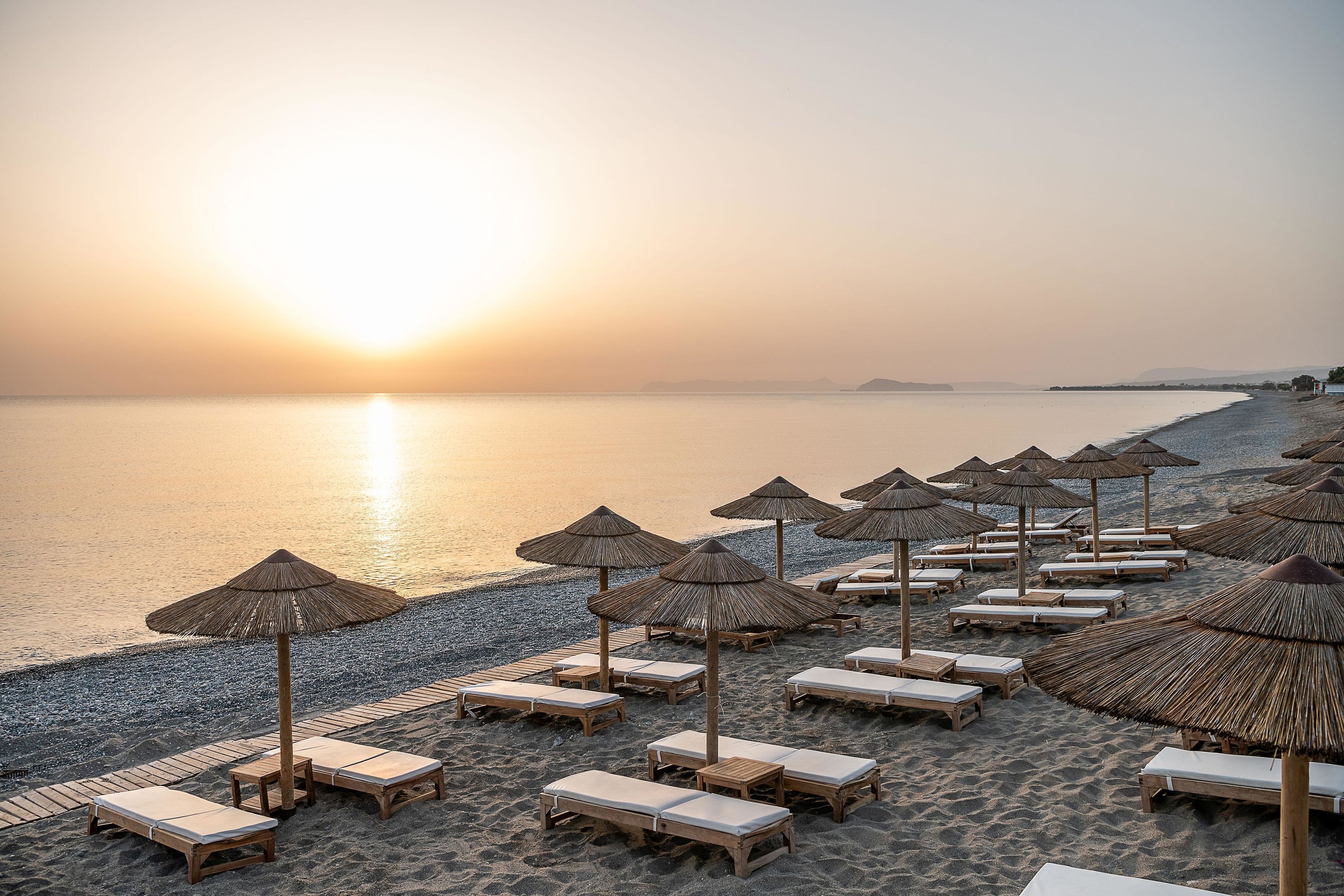 En la playa, sillas reclinables de playa, sombrillas, toallas de playa