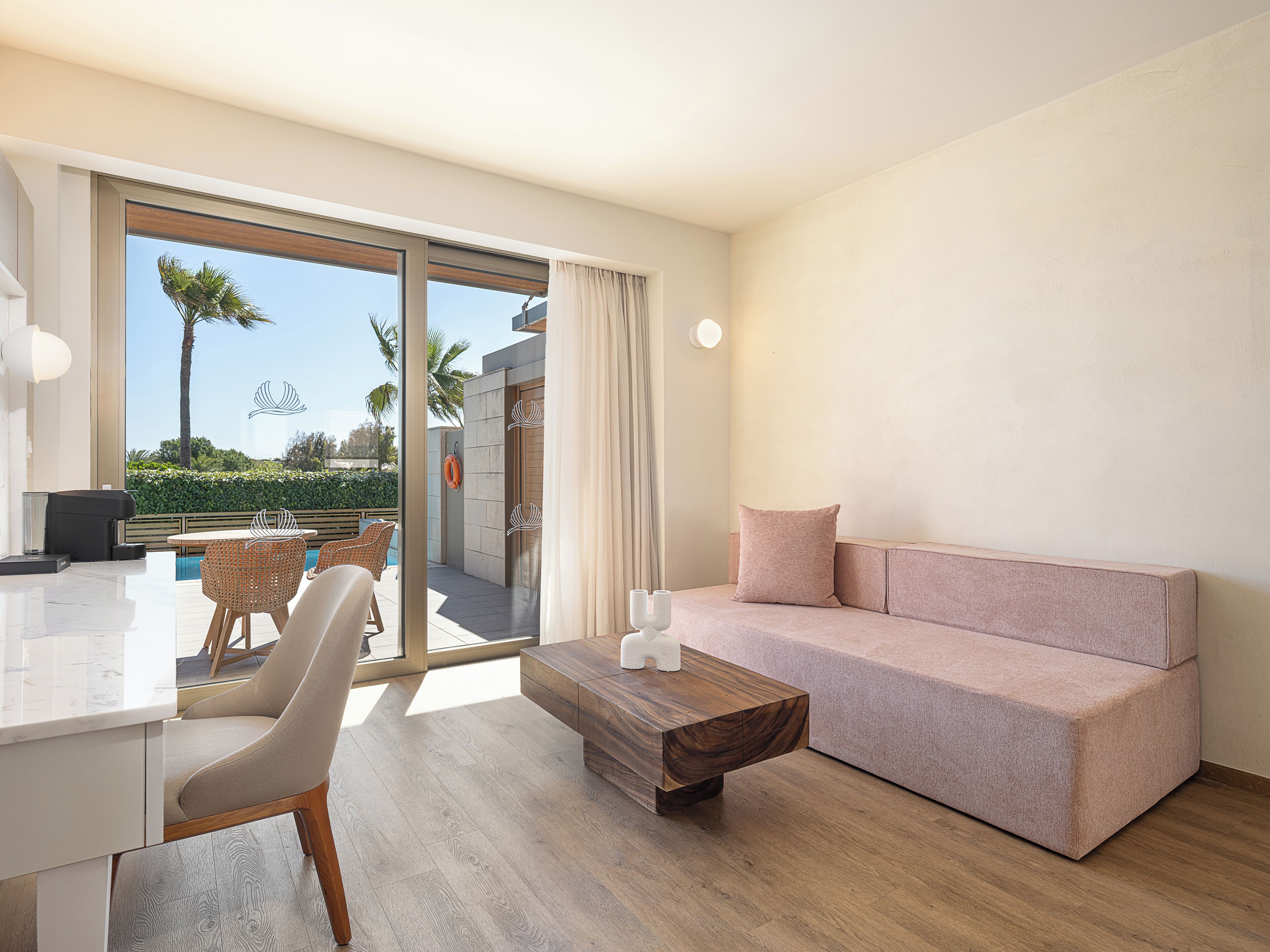 A modern living room with a sofa, a coffee table, and a dining area with chairs and a table.