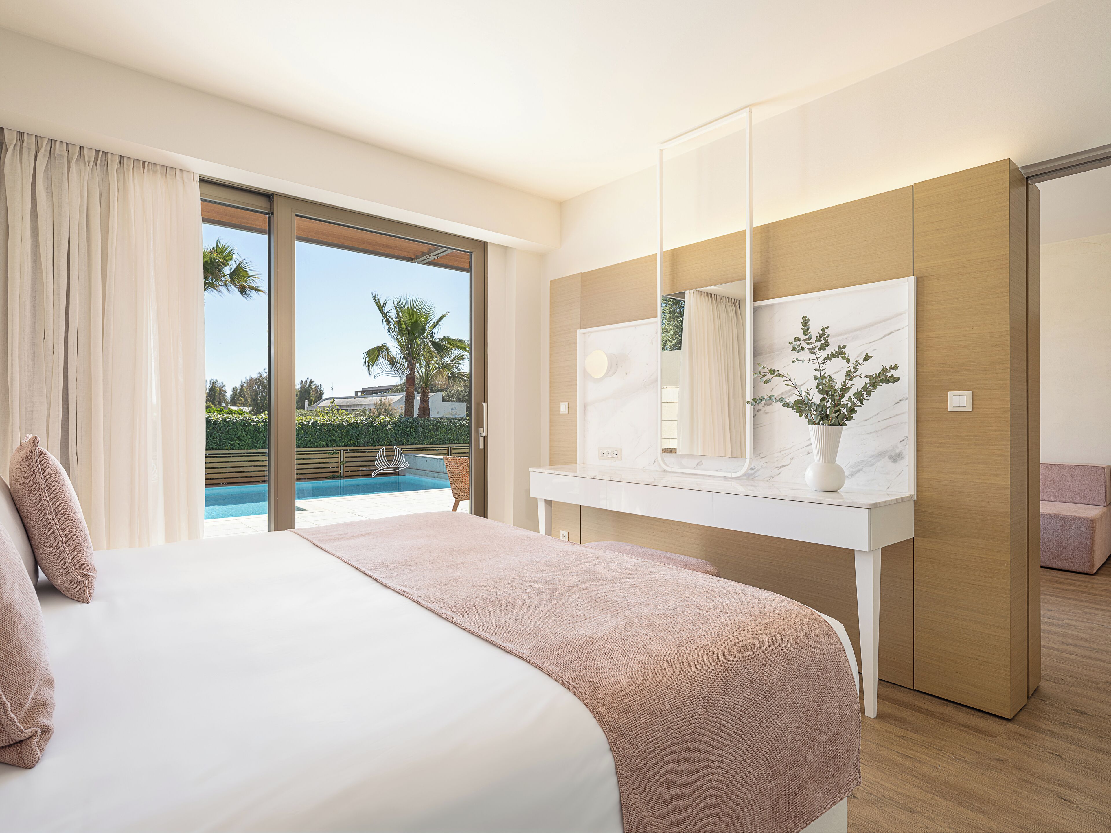 Una habitación de hotel moderna con una cama grande, un baño con encimera de mármol y vistas a una piscina.