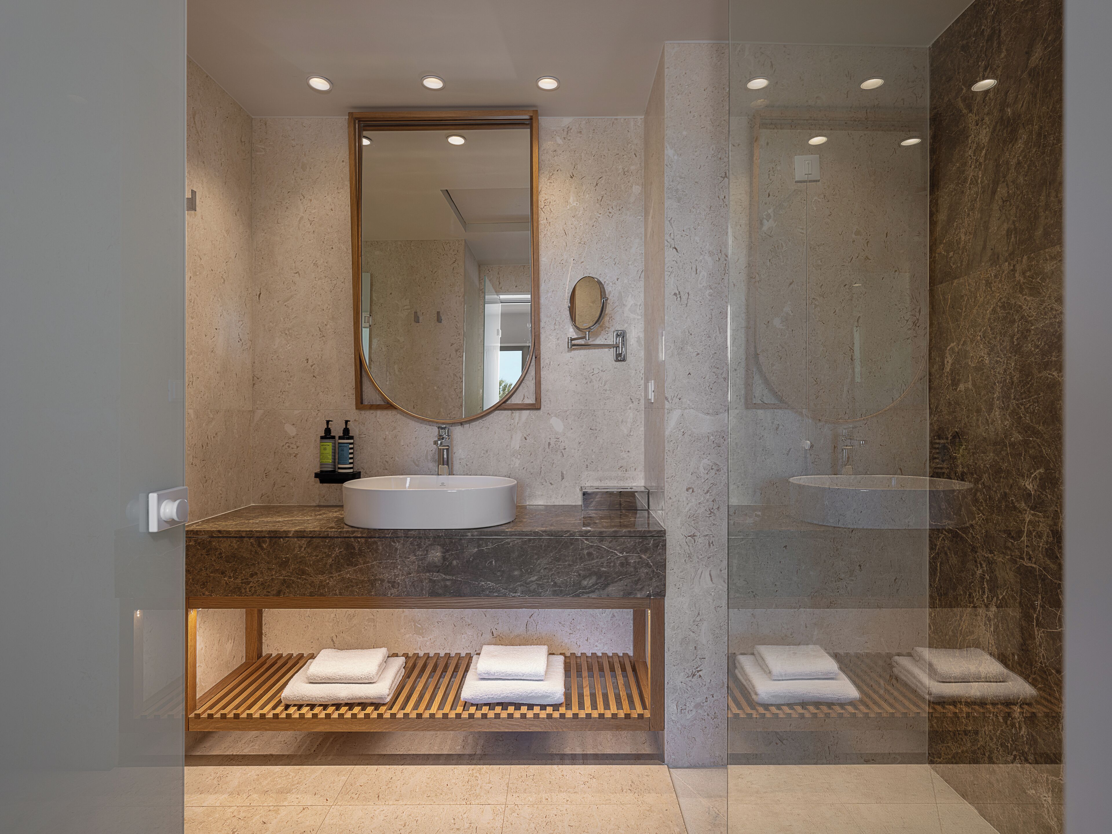 A modern bathroom with two sinks, a large mirror, and a glass shower enclosure.