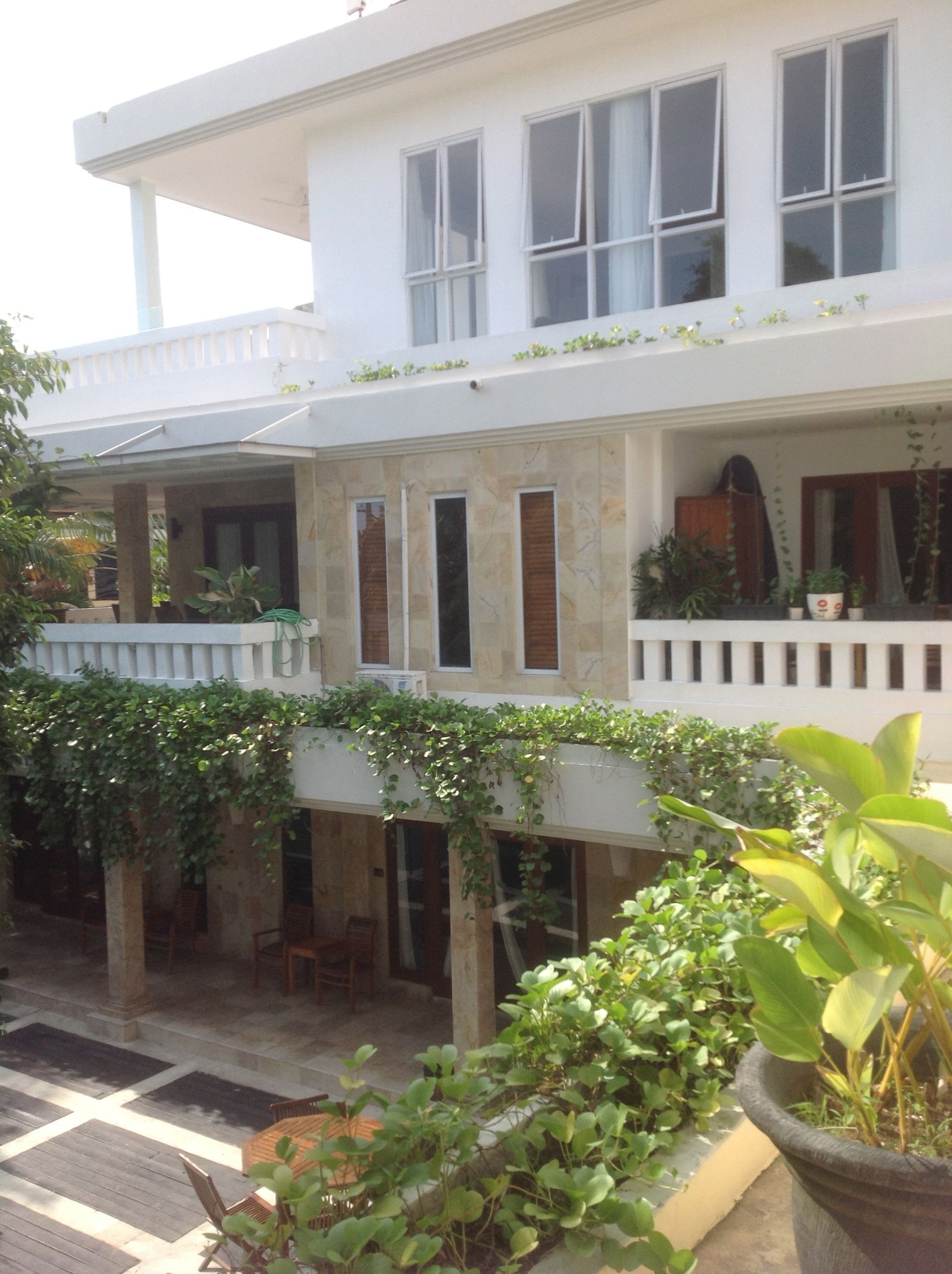 A two-story building with a covered patio area, stone pillars, and potted plants.
