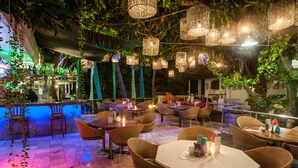 An outdoor restaurant with wicker furniture, hanging lanterns, and a bar area with bottles. - Bali Mystique Hotel and Apartments (Keroboken Kelod)