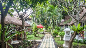 A garden pathway with thatched-roof huts, potted plants, and a checkered tile floor. - Bali Mystique Hotel and Apartments (Keroboken Kelod)