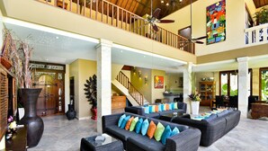 A spacious, multi-level living area with a high ceiling, a balcony, and a staircase. - Bali Mystique Hotel and Apartments (Keroboken Kelod)