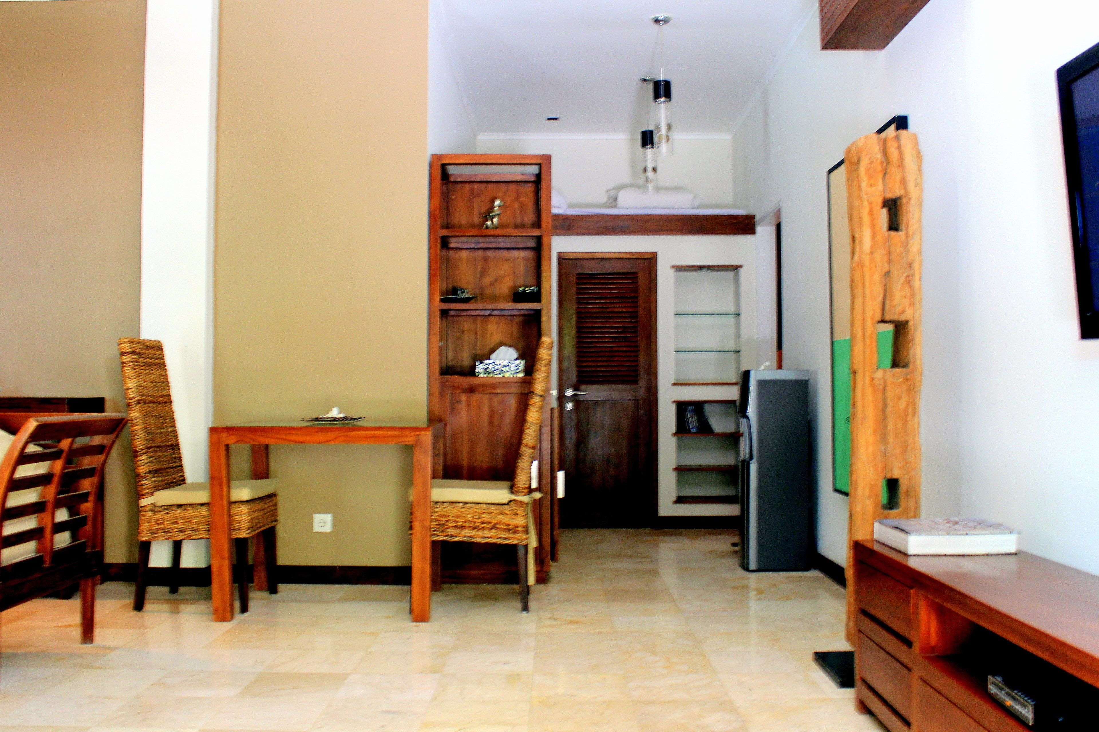 A dining area with a wooden table and chairs, a built-in bookshelf, and a television on a wooden stand.