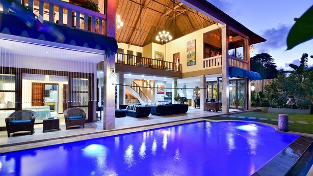 A modern multi-story house with a large indoor swimming pool, a balcony, and a staircase leading to the upper floor. - Bali Mystique Hotel and Apartments (Keroboken Kelod)