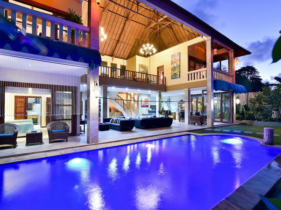 Una casa moderna de varios pisos con una amplia piscina interior, un balcón y una escalera que conduce al piso superior.