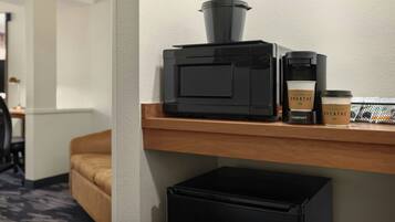 Een koffieapparaat en een koffiekop op een houten plank in een hotelkamer.