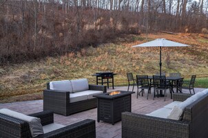 Un patio al aire libre con mobiliario de mimbre, una mesa, sillas y una chimenea.
