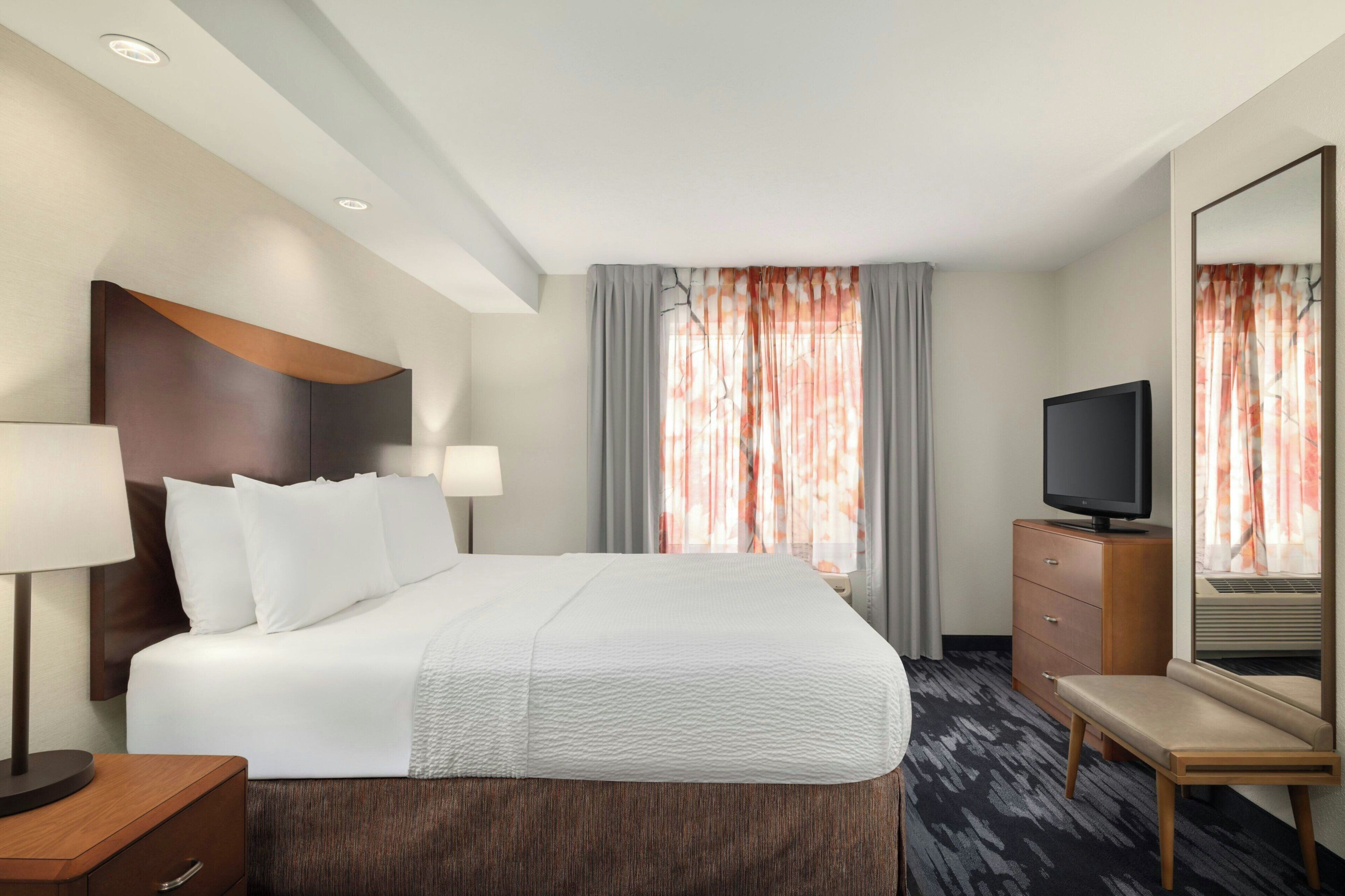 Una habitación de hotel con cama, televisión, escritorio y espejo.