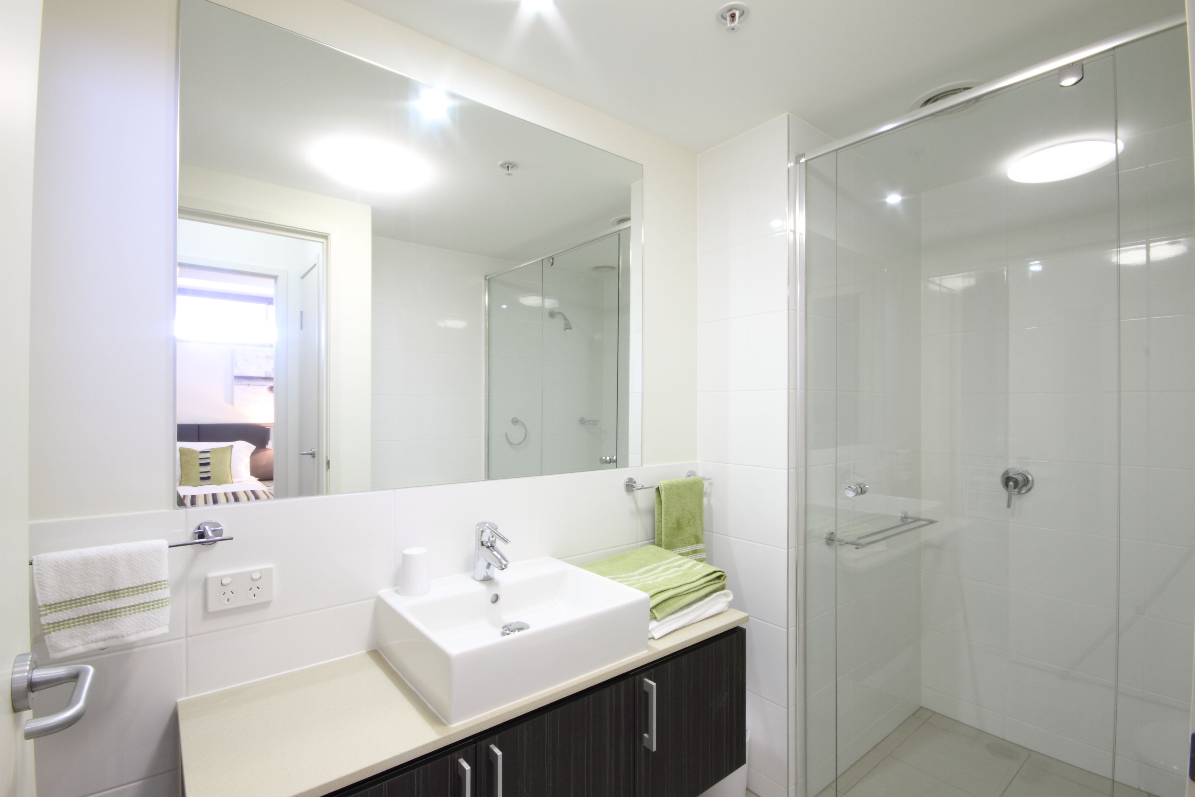 Ein modernes Badezimmer mit Waschbecken, Spiegel und Duschkabine aus Glas.