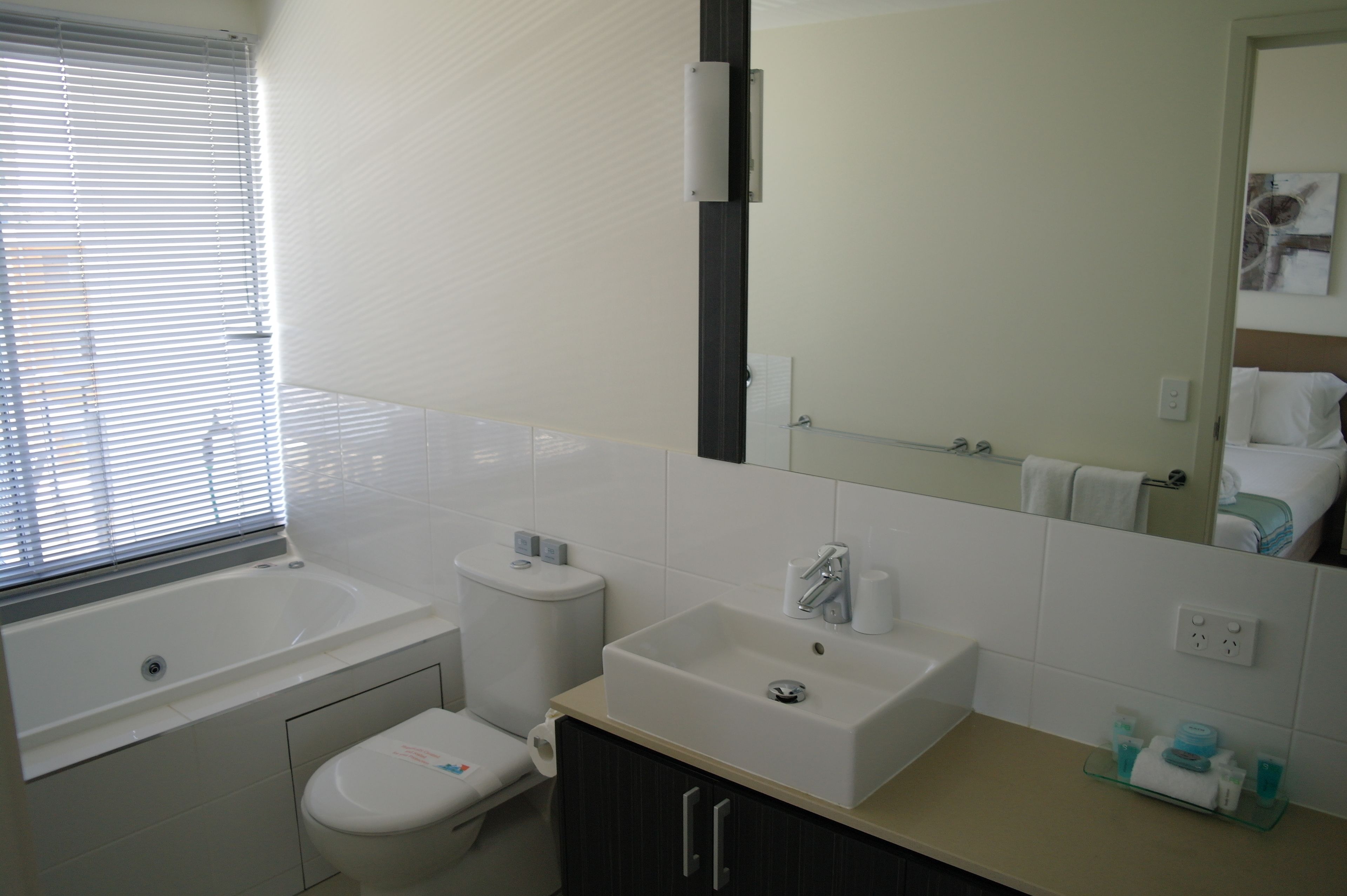 Ein Badezimmer mit Badewanne, Toilette, Waschbecken und Spiegel.