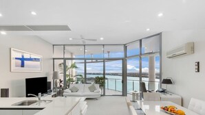 A modern living room with a large glass door leading to a balcony with a city view.