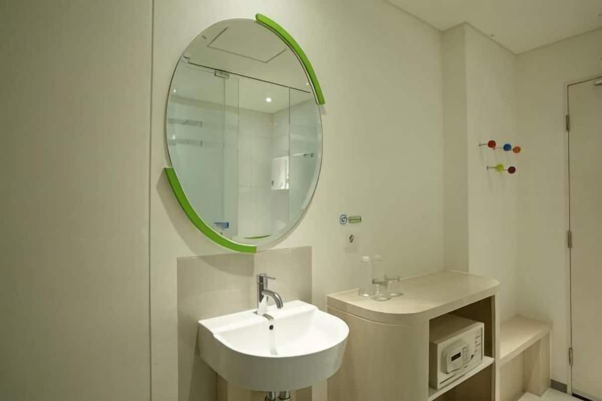 A bathroom with a round mirror, a white sink, and a small shelf.