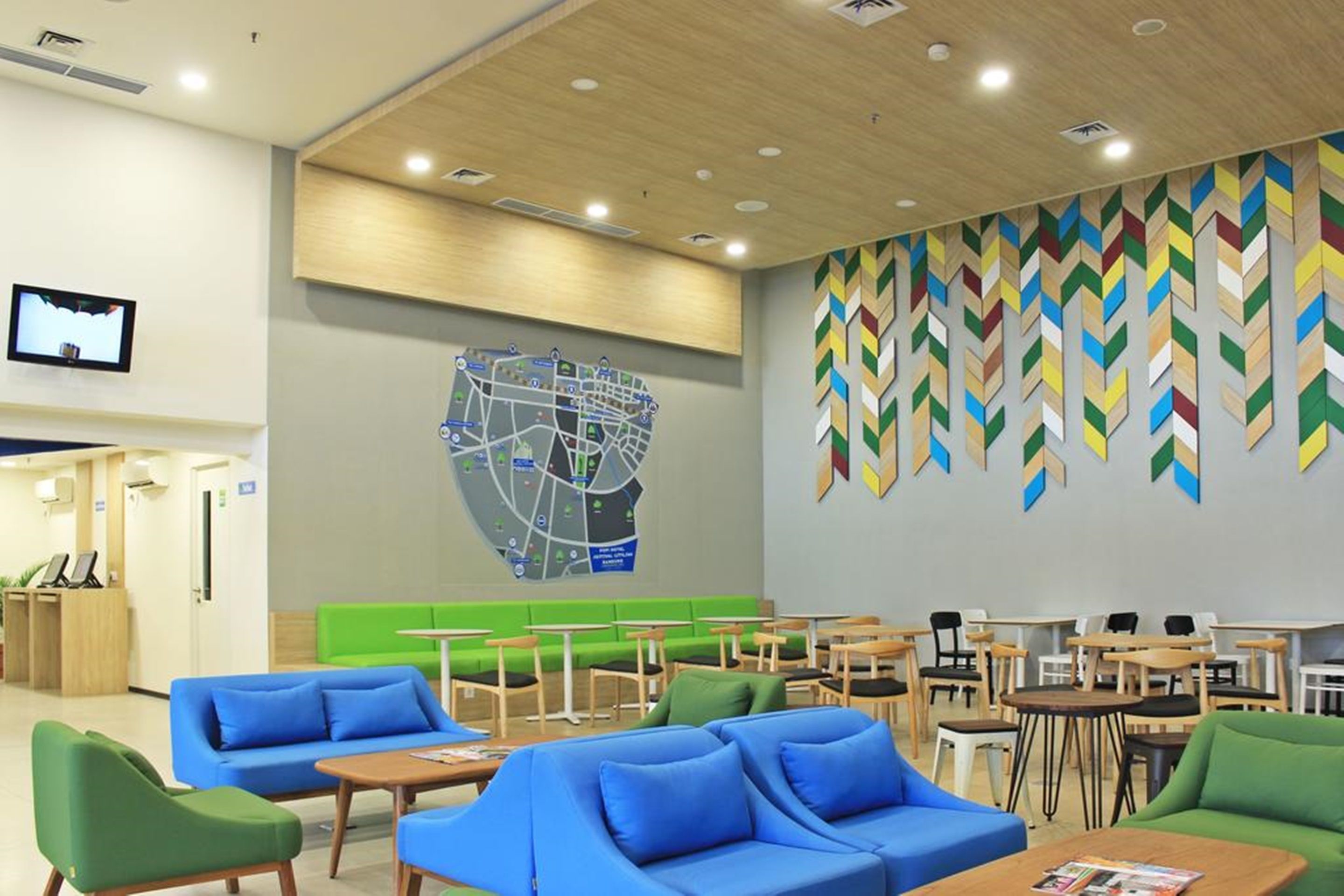 A modern waiting area with green and blue seating, a map on the wall, and a reception desk.