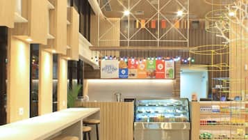 A modern cafe with a wooden interior, a counter with stools, and a display case with pastries.