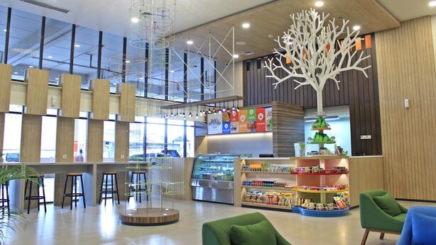 A spacious lobby with a central seating area, a staircase, and a food kiosk. -  POP! Hotel Festival Citylink Bandung (Bandung)