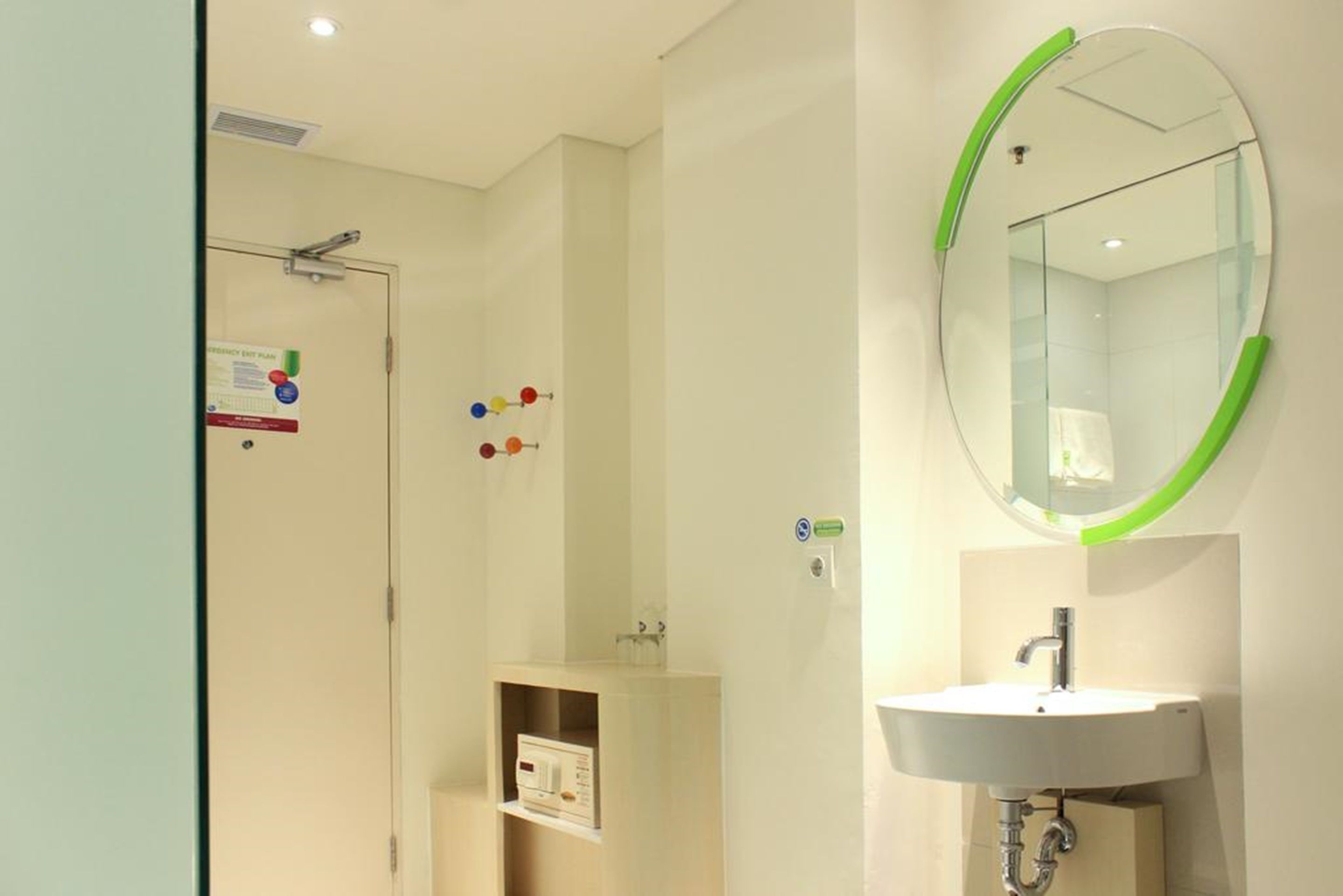 A bathroom with a white sink, a mirror with a green frame, and a shower area.
