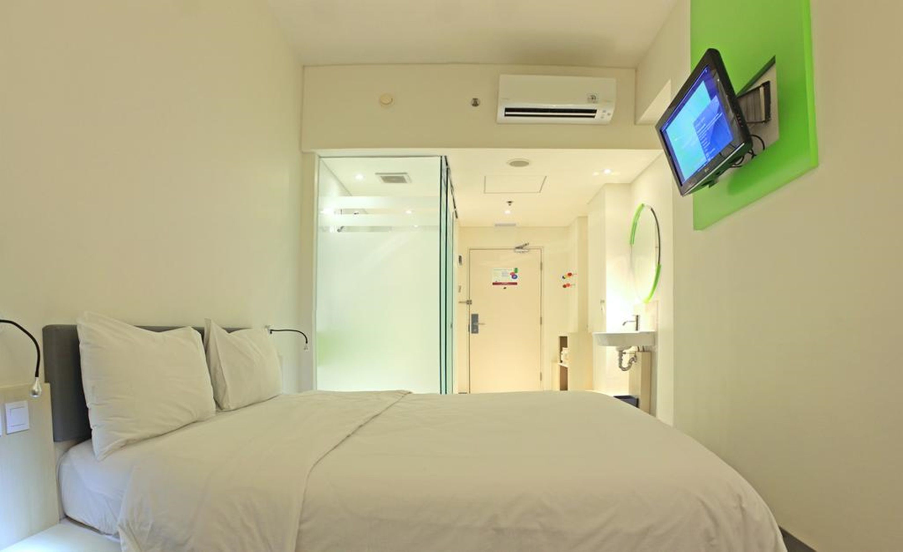 Une chambre d’hôtel équipée d’un lit, d’un téléviseur fixé au mur et d’un appareil de climatisation.