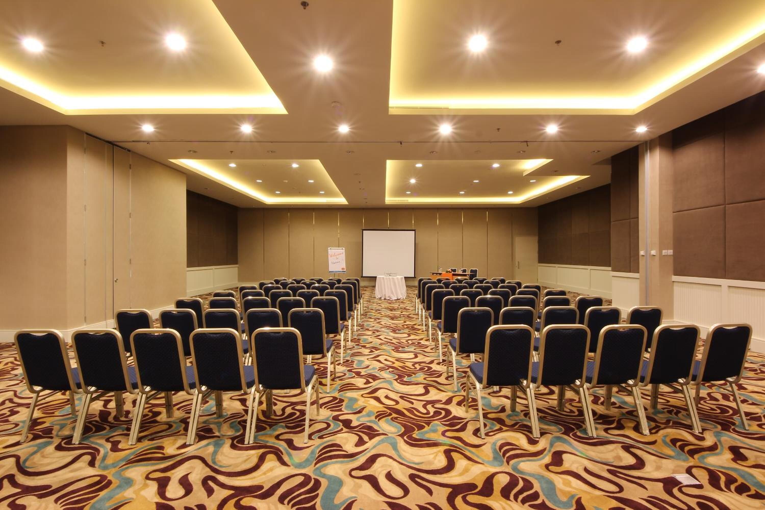 A conference room with rows of chairs, a whiteboard, and a carpeted floor.