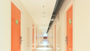A hotel corridor with orange doors, each marked with a number. -  POP! Hotel Festival Citylink Bandung (Bandung)