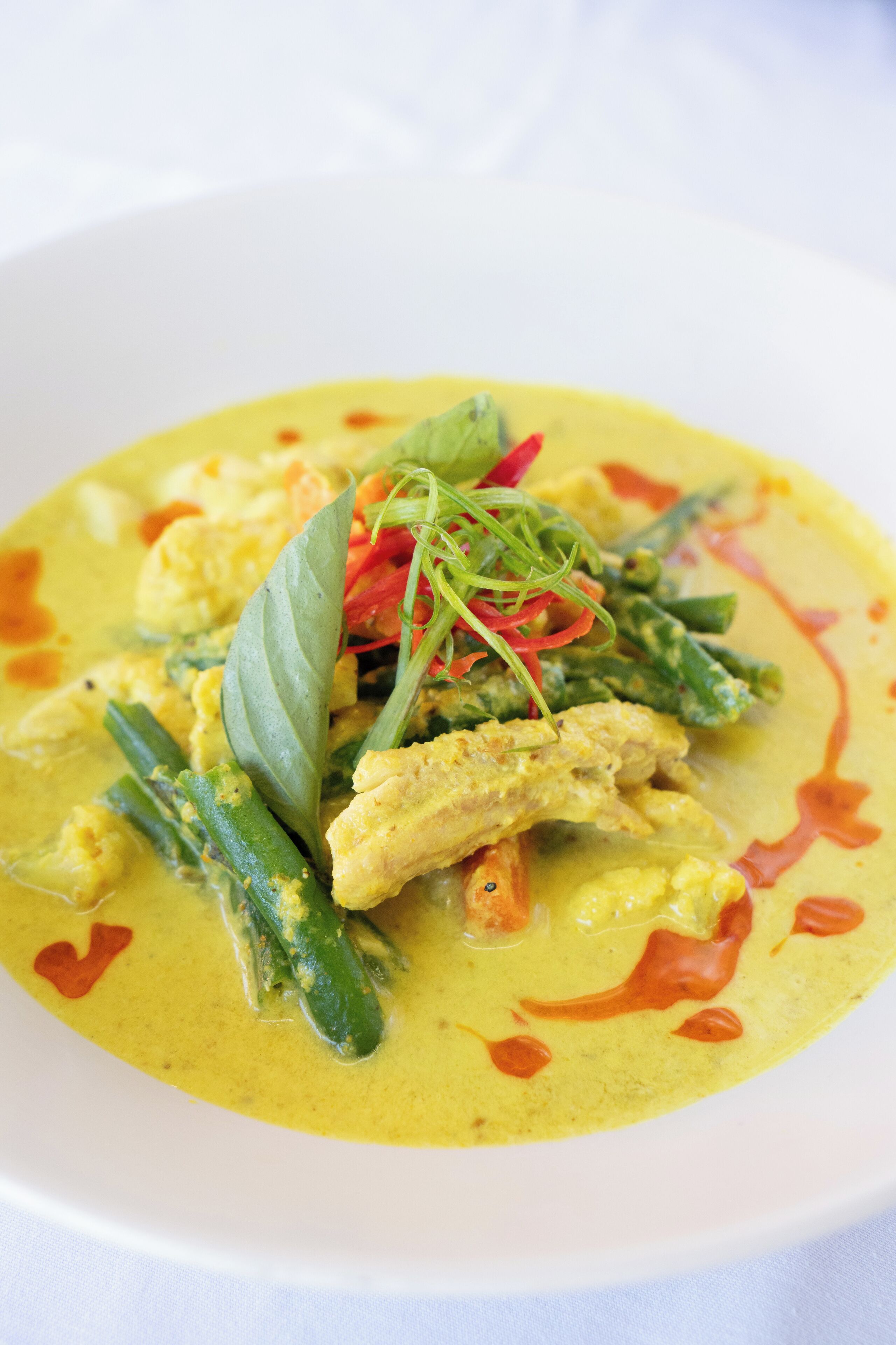 A dish with green beans, red chili, and a yellow sauce.