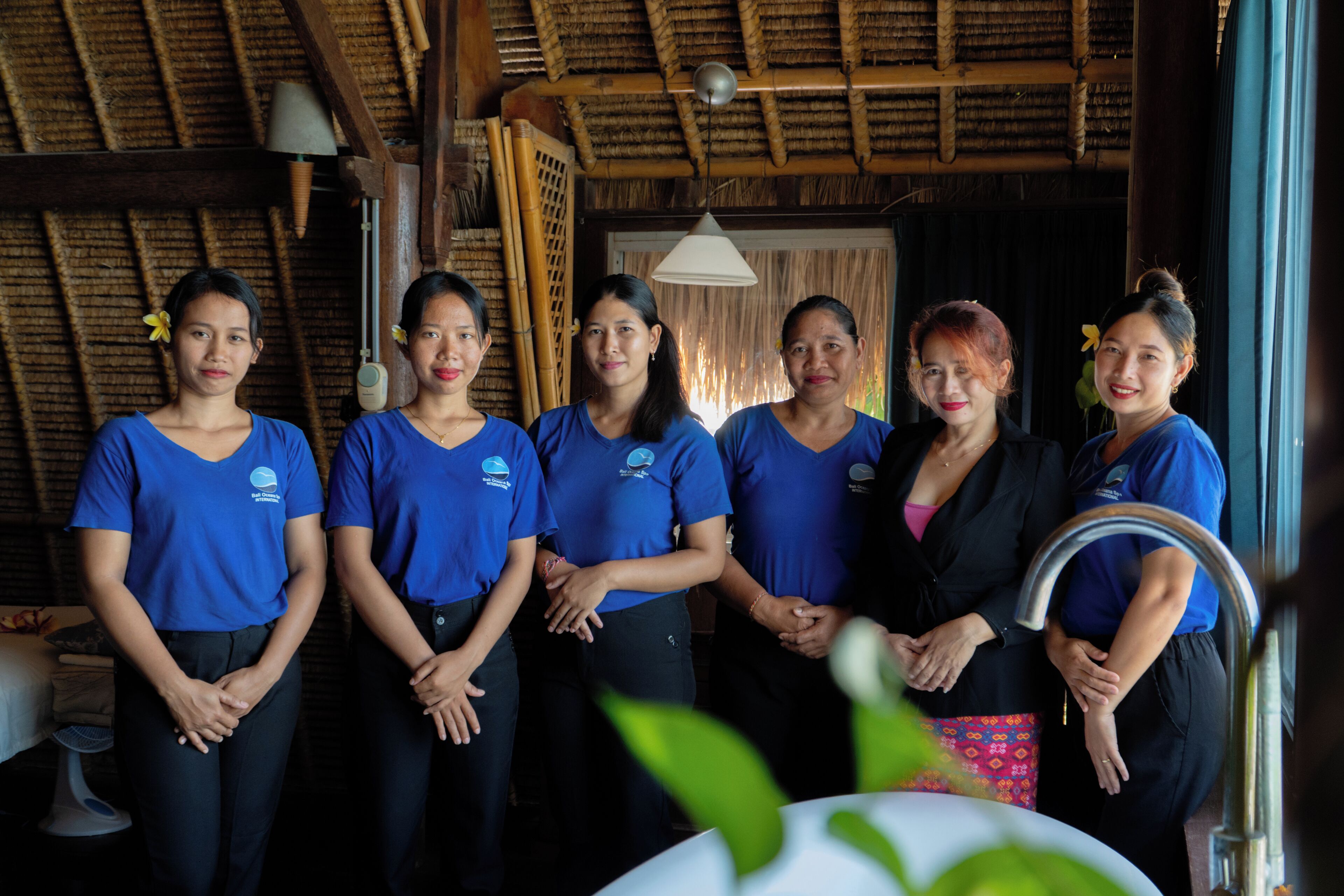 A group of people in a room with a thatched roof and bamboo walls.