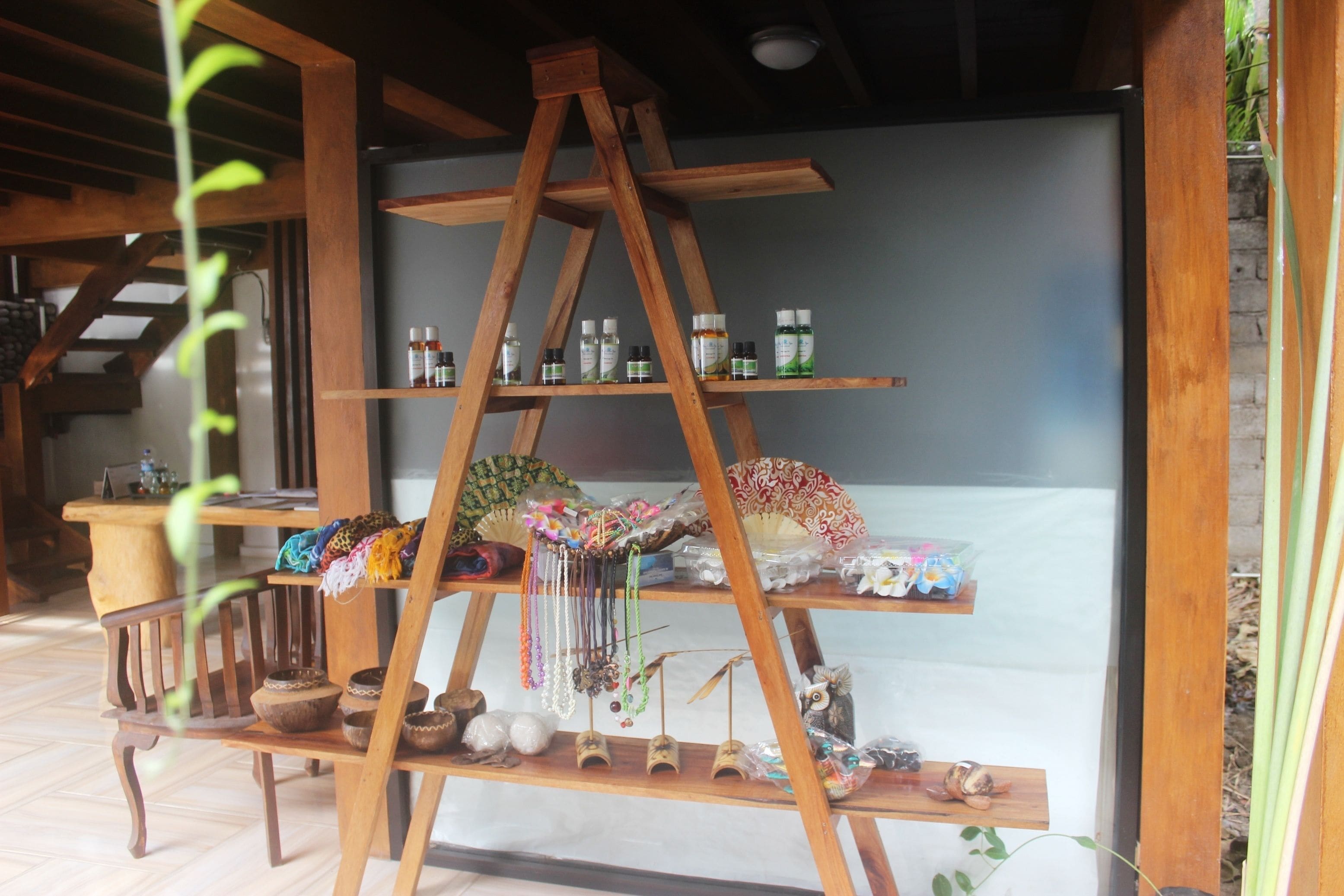 Une étagère en bois où sont exposés divers objets, notamment des bouteilles, un ventilateur et des objets décoratifs.