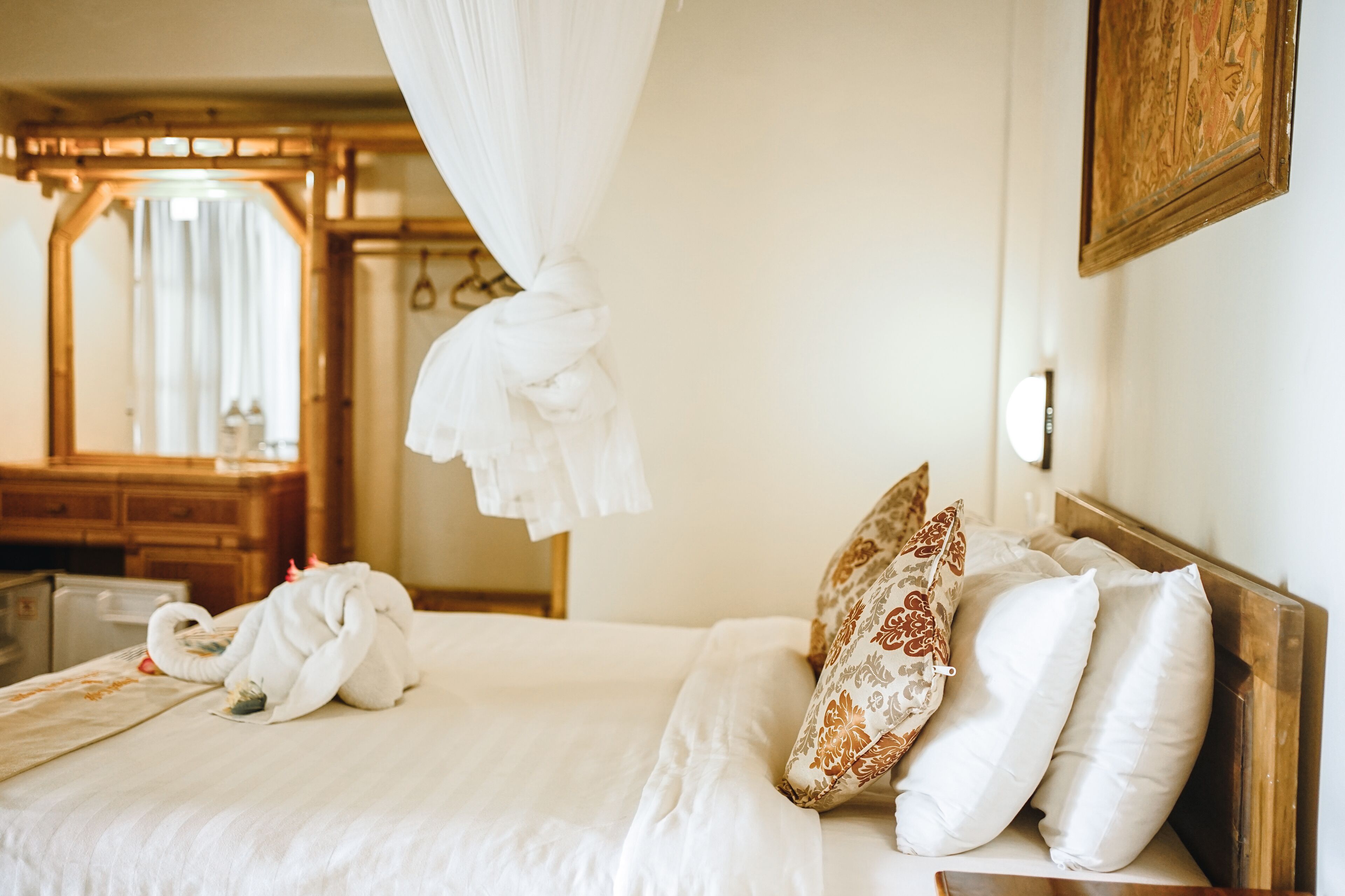 A hotel room with a bed, a wooden headboard, a mirror, and a wooden cabinet.