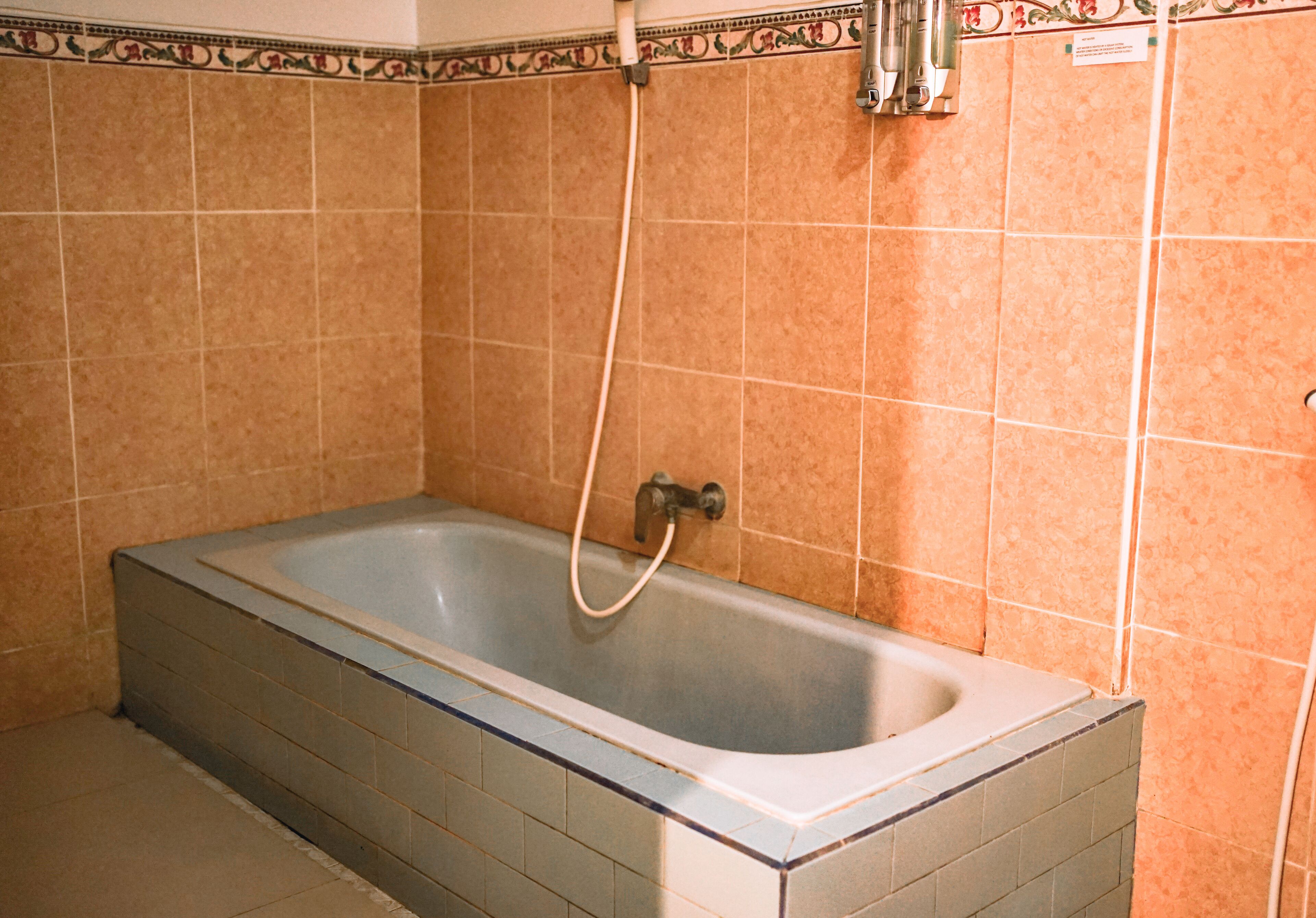 A bathroom with a bathtub, tiled walls, and a showerhead.